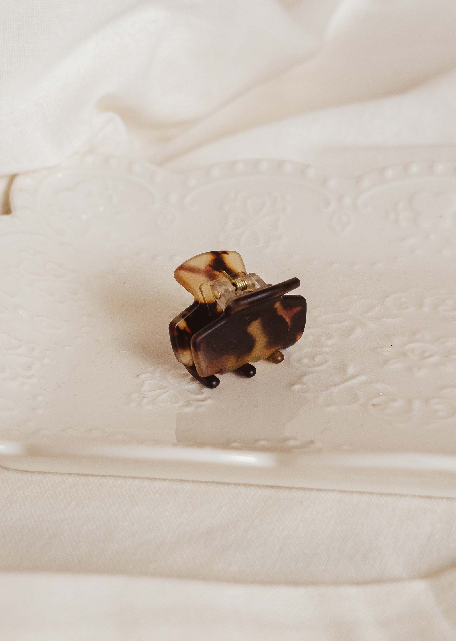 Tortoise Matte mini hair clip in a decorative white plate