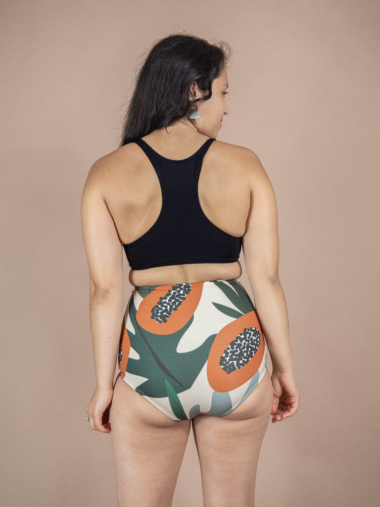 Vue de dos d'une femme portant un bas de bikini taille haute Mimi & August Bermudes Papaya Extra avec un imprimé de papaye.