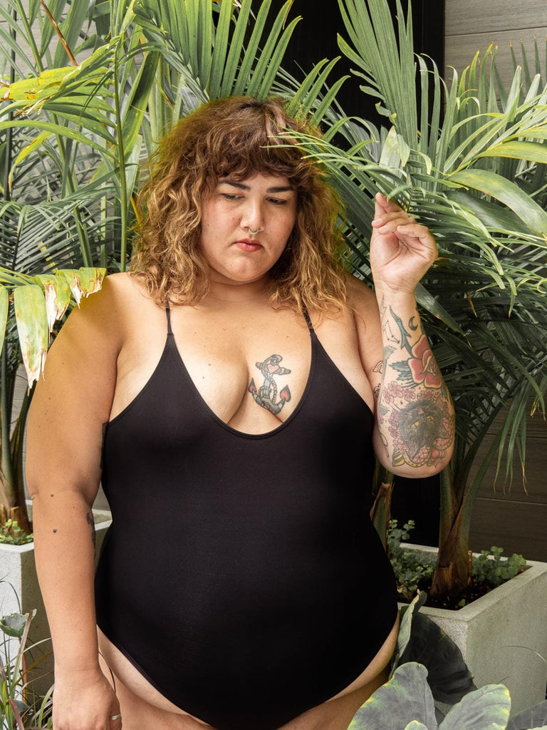 A plus size woman wearing a Black Water Drop one-piece bathing suit by Mimi & August.