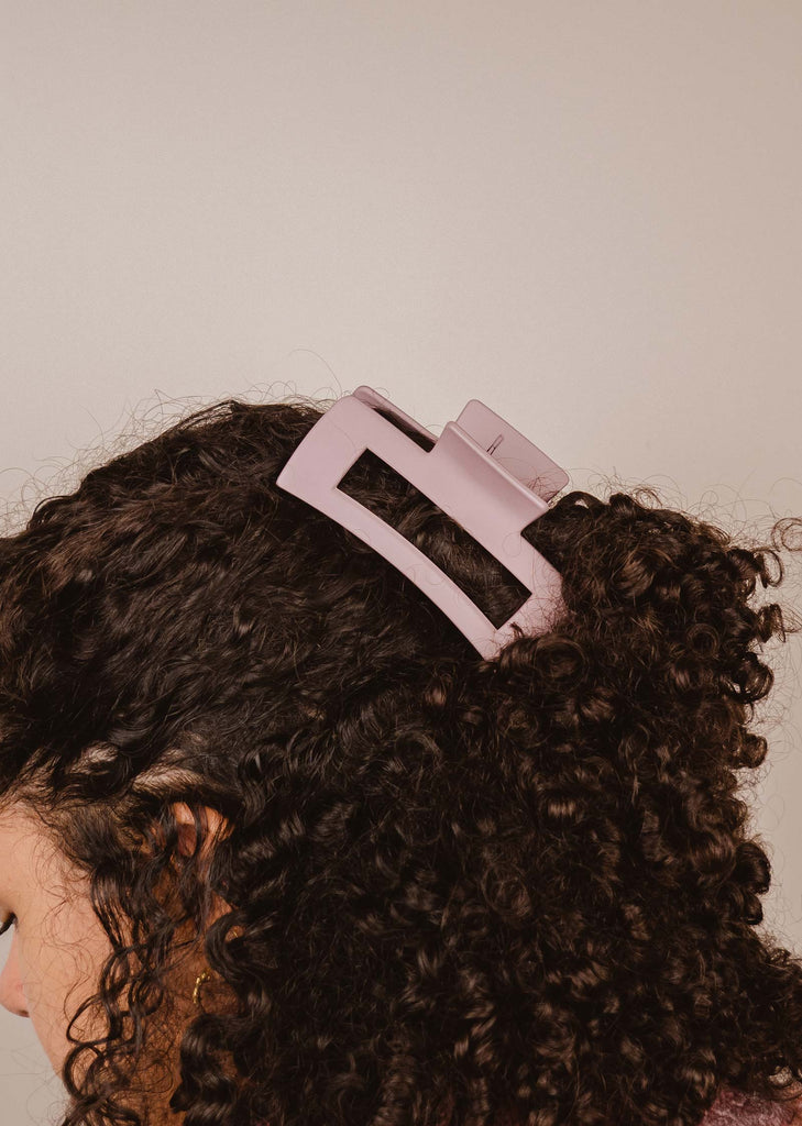 Functional lilac daisy hair clip attached to a curly hair