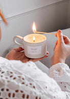 Person lighting a reusable eucalyptus candle in a ceramic cup with a wooden matchstick