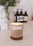 Reusable fir tree candle Foresta in ceramic cup on kitchen counter with blurred background.