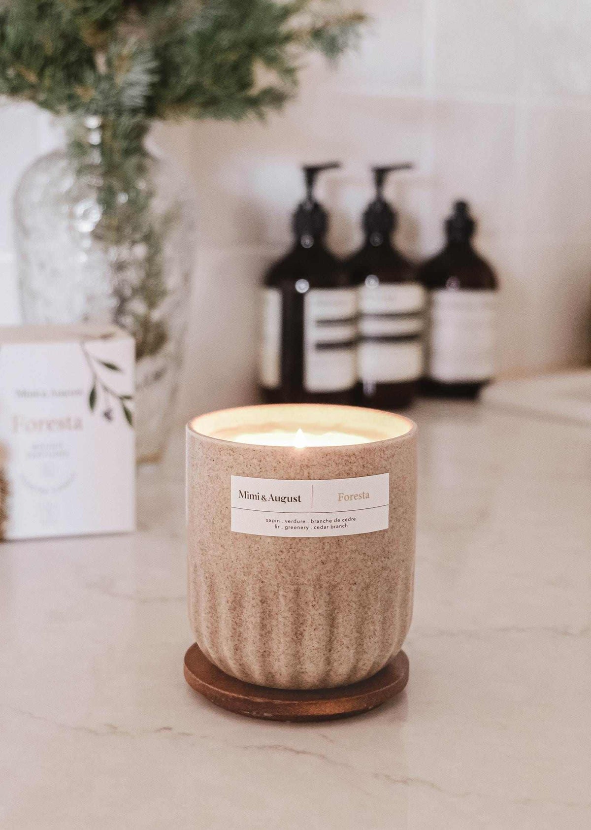 Reusable fir tree candle Foresta in ceramic cup on kitchen counter with blurred background.