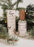Forest room spray Foresta by Mimi & August with fir needle and cedarwood scent surrounded by evergreen branches