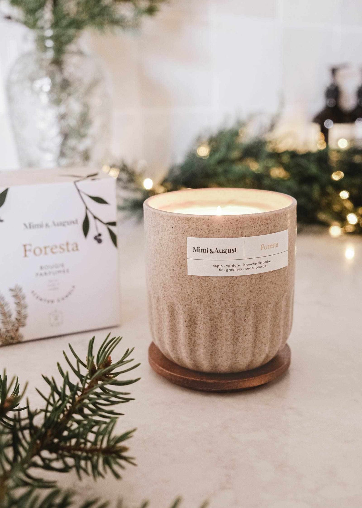 Reusable fir tree candle in ceramic cup with soft glowing flame and festive greenery background