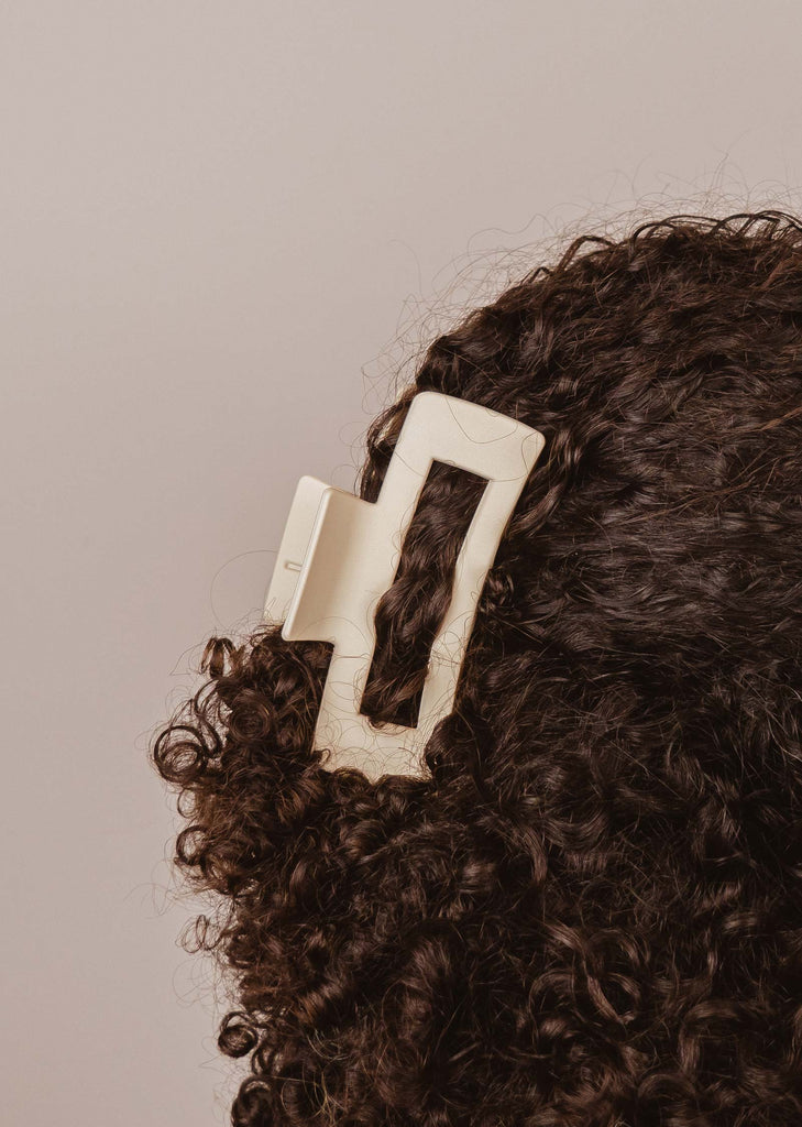 Pince à cheveux Marseille ivoire avec des griffes qui tiennent sur les cheveux noirs bouclés