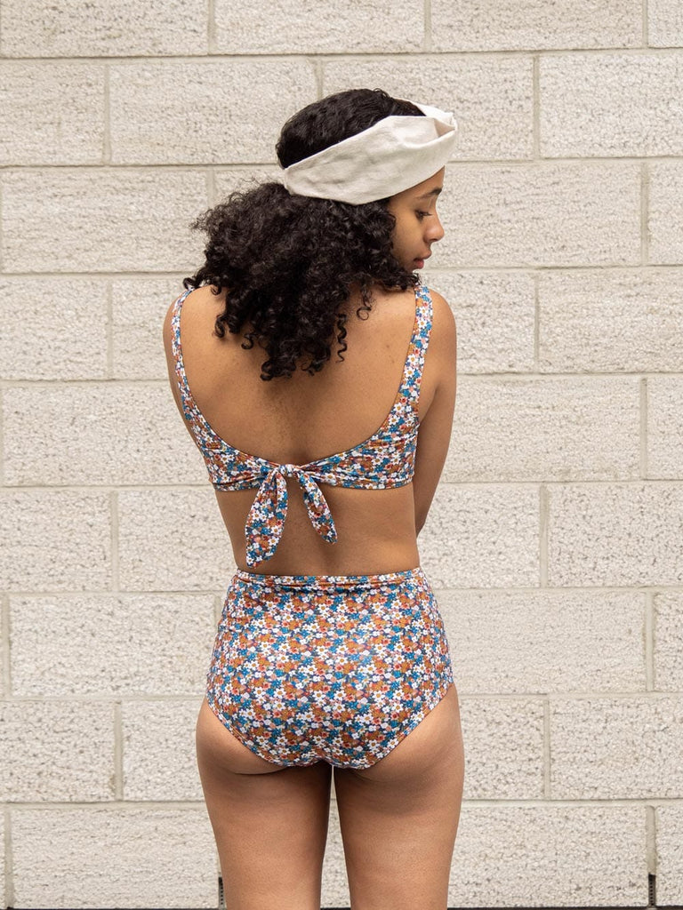 The back view of a woman in Mimi & August's Paloma Floral Bouquet High Waist Bikini Bottom providing coverage.