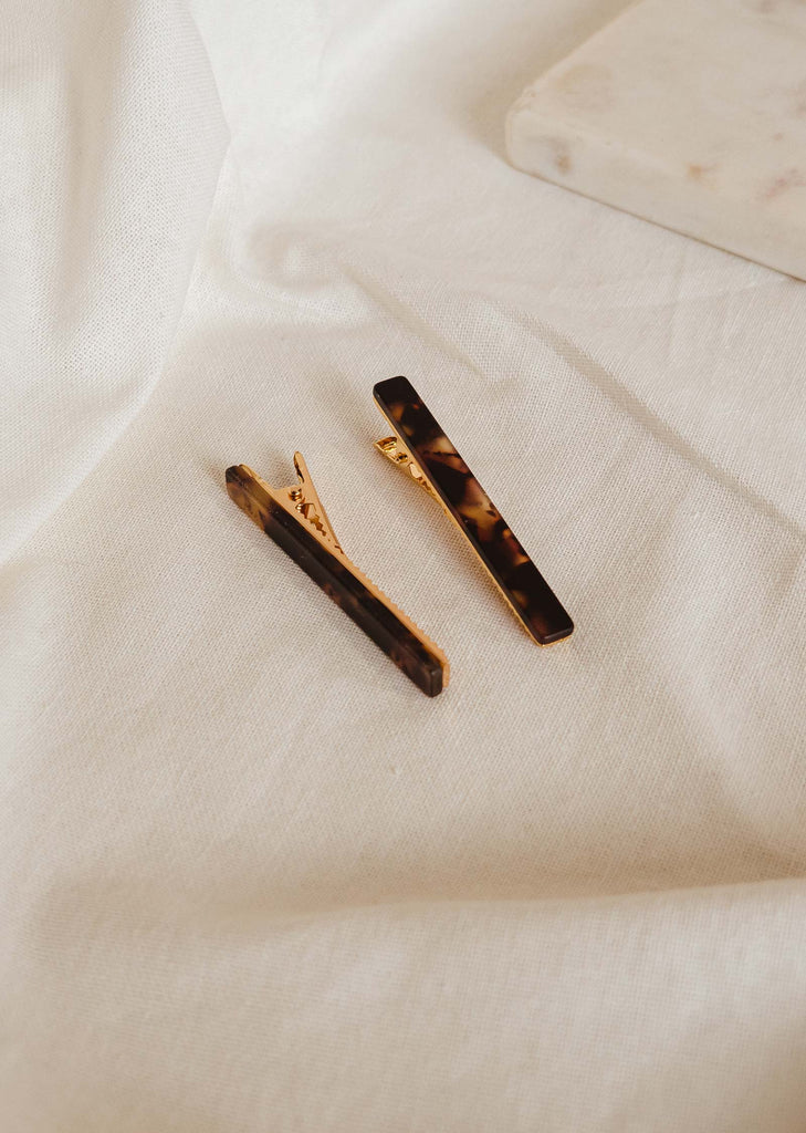 duo of bar-shaped hair clips that are on a tablecloth