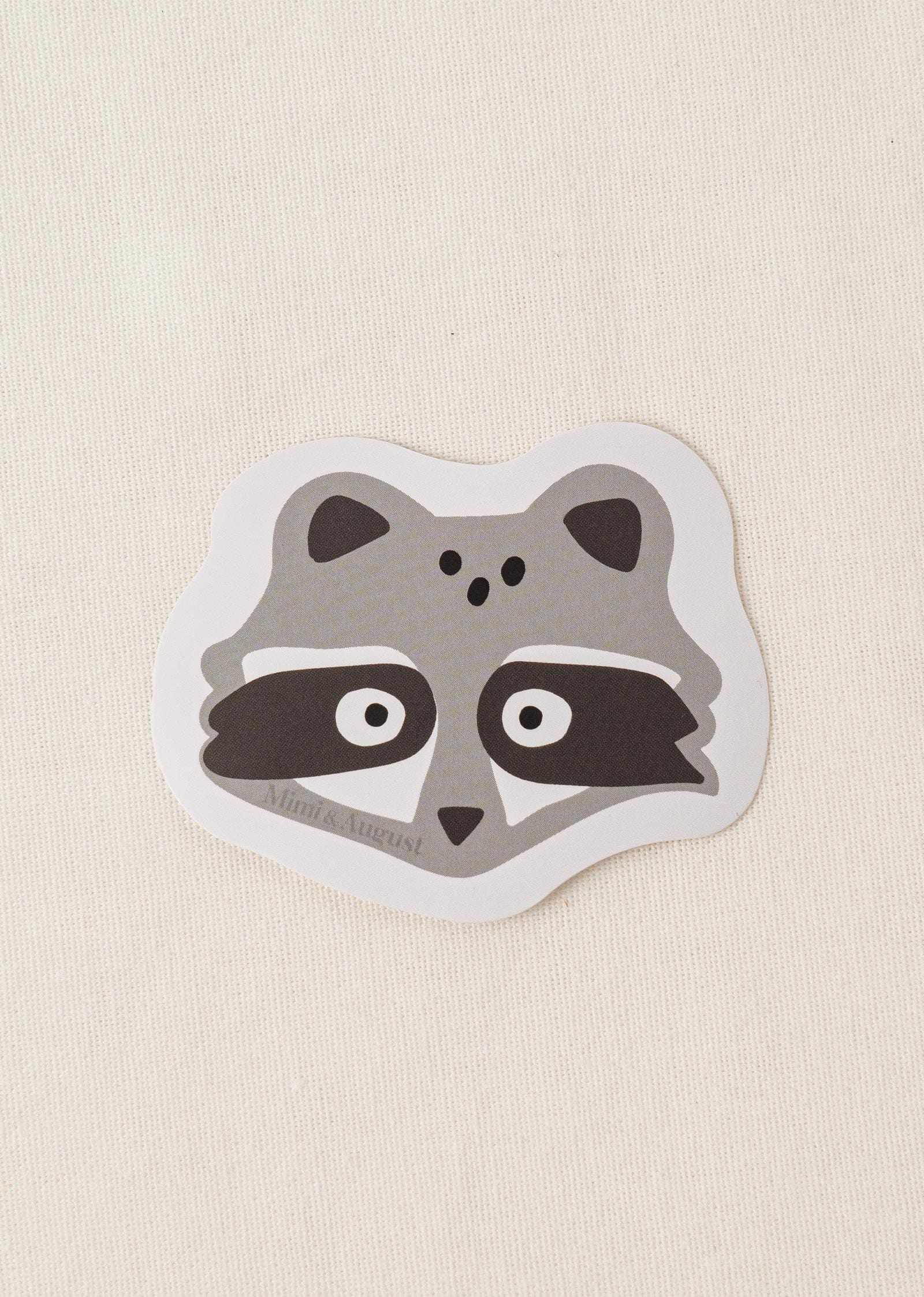 Cute vinyl sticker of a raccoon face with matte finish and white border