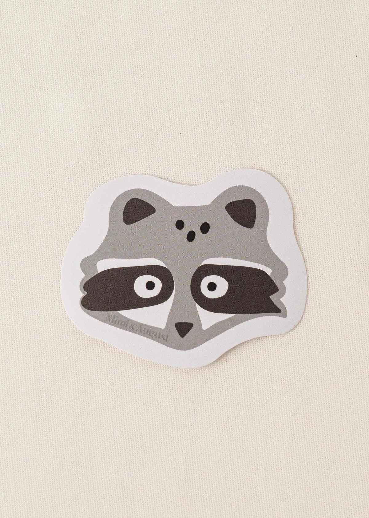 Cute vinyl sticker of a raccoon face with matte finish and white border