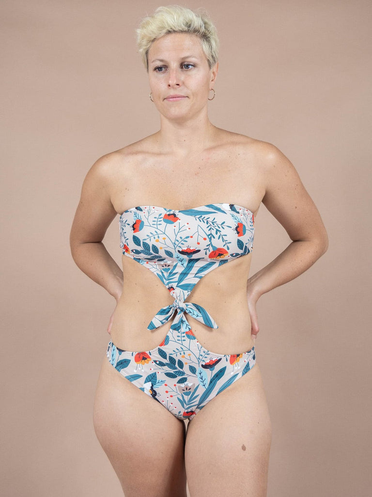 Une femme portant un maillot de bain une pièce Wild Flower Knot de Mimi & August, dans un style bohème.